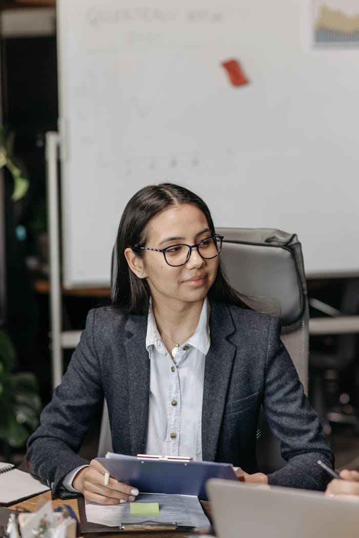 Confident businesswoman holding clipboard during a meeting in an office setting.